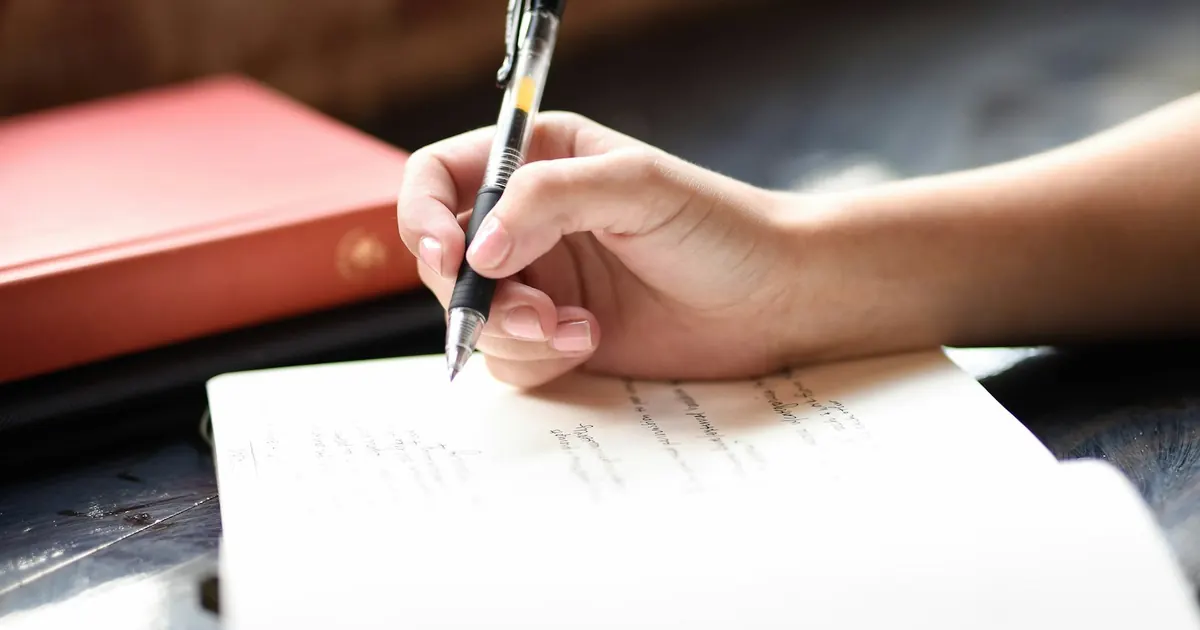 Persona escribiendo a mano en una hoja de papel