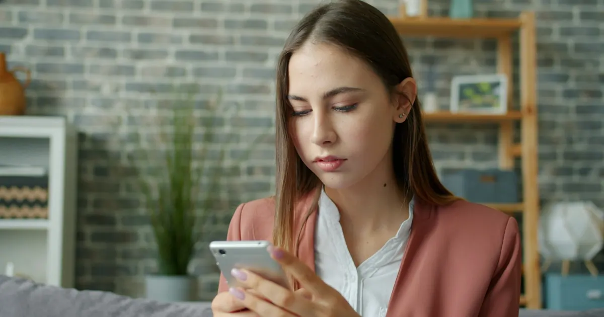 Mujer joven revisando su celular en casa