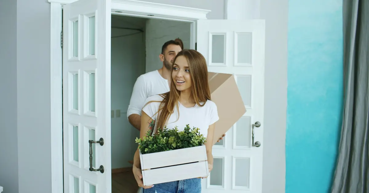Pareja cargando cajas al entrar a su nueva casa