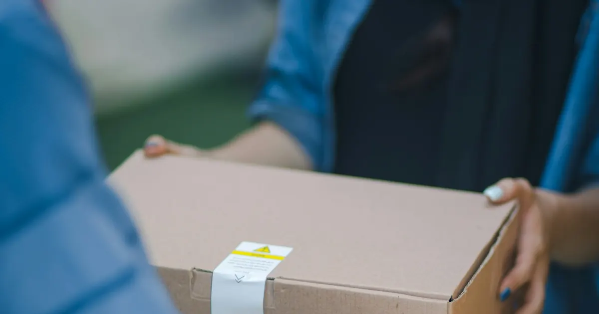 Repartidor entregando una caja de cartón en mano