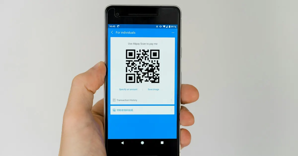 Mano sosteniendo un celular que muestra un código QR