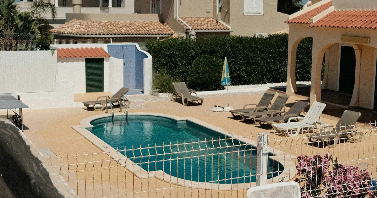 Alberca de un residencial con camastros y casas alrededor