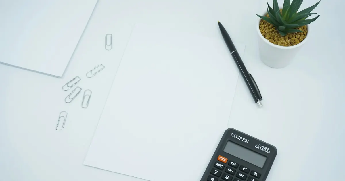 Calculadora y pluma sobre hojas de papel en un escritorio